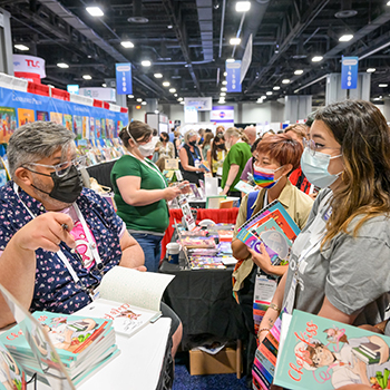 Author Jarrett Melendez (left) signs copies of his graphic novel Chef’s Kiss at the Oni Press booth.